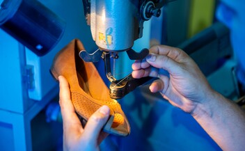 Schuhmacher näht einen braunen Lederschuh an einer Maschine